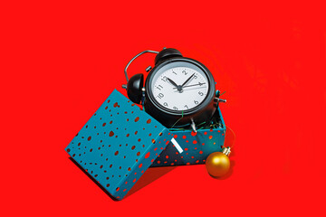 Alarm clock with headphones and gift box on red