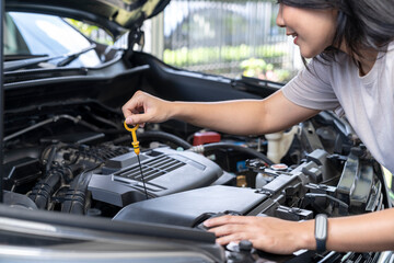 Fototapeta na wymiar A woman's hand checking the engine oil of a car at home