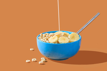 Healthy cereal bowl with banana slices and milk pour