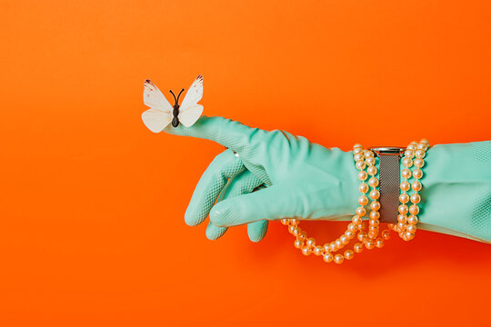 Elegant hand in glove with butterfly and pearls on orange