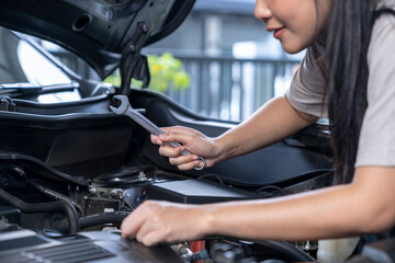 A young woman is repairing a car by herself at home