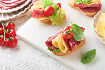 Salami sandwich. Delicious toasted sandwiches with slice salami, cheddar cheese lettuce and tomatoes cherry on white marble background. Restaurant menu, cafe, recipe or article concept. Mock up.