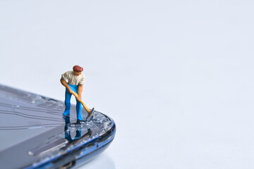 Miniature person with pickaxe damages the smartphone display, white background, copy space
