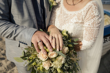 Brautpaar präsentiert Eheringe und Brautstrauß - 695365171