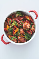 Stewed chicken fillet with vegetables in pan, white background.