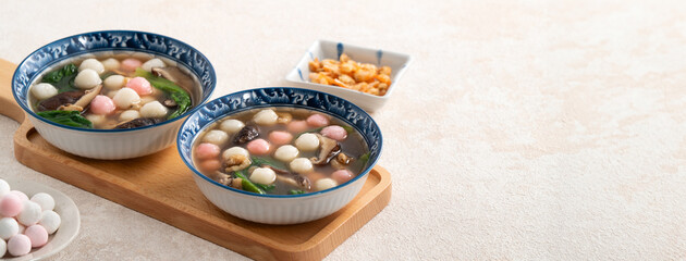 Eating red and white small tangyuan with savory soup and vegetable.