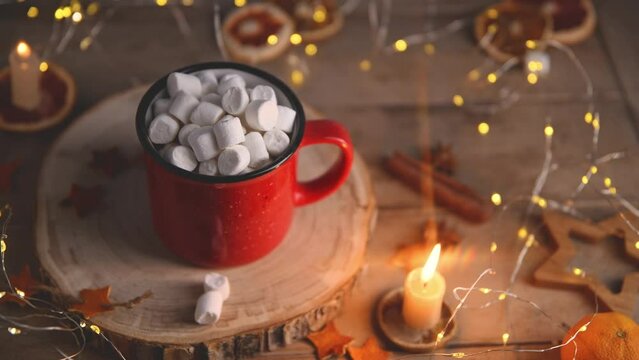 cute cozy winter composition 2024. red mug, marshmallows, Christmas lights and candle. new year and christmas, warmth, comfort, cozy
