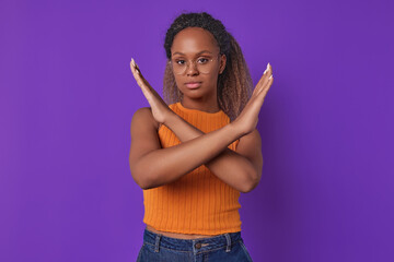 Young beautiful attractive African American woman demonstrates stop gesture by crossing arms and...