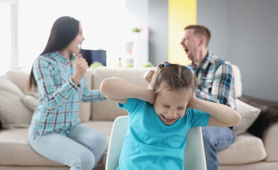 Obraz na płótnie Canvas Little girl closing her ears against background of swearing parents at home. How are problems of adults reflected on child psyche concept