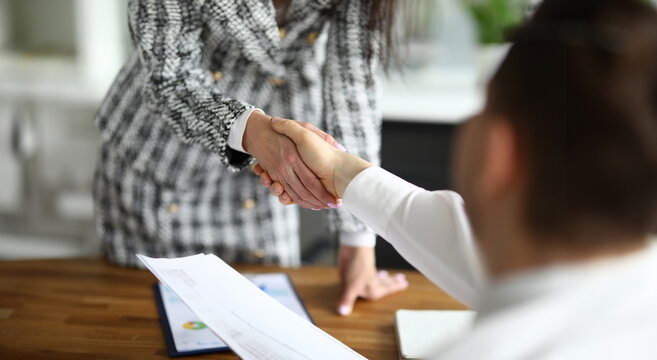 Close-up of businesswoman shaking hands with guest. Young woman in presentable luxury suit in office. Signing contract and make deal. Successful financial company concept
