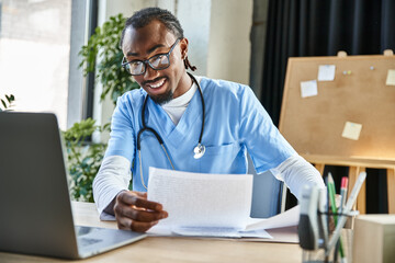 attractive joyous african american doctor holding notes during online consultation, telemedicine
