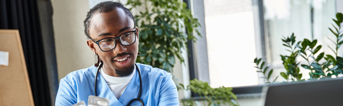 cheerful african american doctor with pills in hand looking at laptop camera, telemedicine, banner
