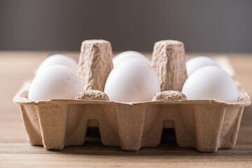 Organic white leghorn egg from free range farm in paper tray on wooden table - obrazy, fototapety, plakaty