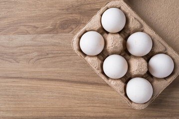 Organic white leghorn egg from free range farm in paper tray on wooden table, Top view
