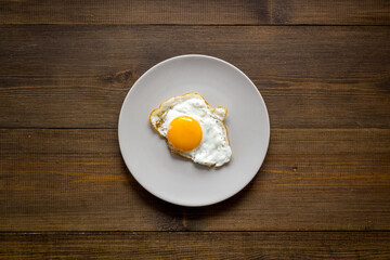 Fast breakfast with one fried egg on plate, top view