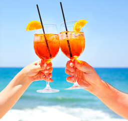 Two cocktail glasses in the hands on sea background