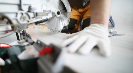 Close-up of professional foreman working with metal electrical equipment. Man in protective white gloves for work. Detailed picture. Renovation and construction site concept