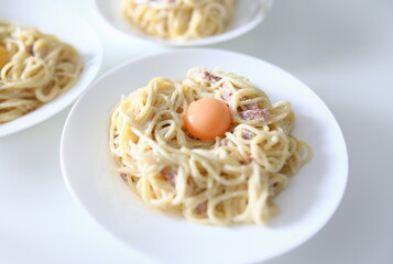 Close-up of delicious pasta with bacon egg and sauce. Bolognese served on white plate for couple. Yummy dinner. Traditional italian food and healthy eating concept