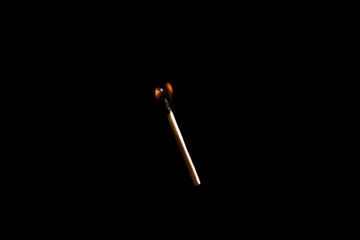 Lit falling match on a black background.