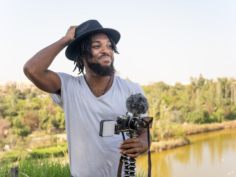 Black male podcaster holding professional camera on tripod