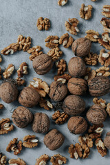 Peeled and shelled walnuts are scattered on a gray background
