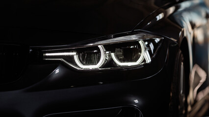 Black modern car headlights - front view. Silhouette of black sports car with headlights close up.