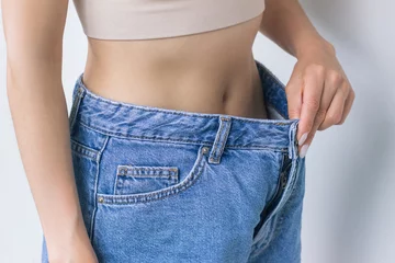 Fotobehang young woman tries on her jeans and shows how big they turned out to be after weight loss. proper nutrition. healthy lifestyle © Ольга Шефер