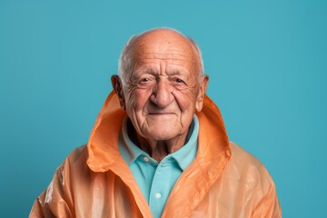 Portrait of a grinning indian elderly man in his 90s wearing a lightweight packable anorak against a pastel blue background. AI Generation