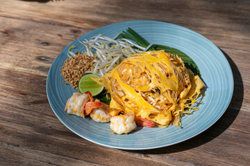 Pad Thai wrapped in eggs vermicelli noodles with prawns pad thai It is delicious street food of Thailand served with fresh bean sprouts and ground peanuts as topping.