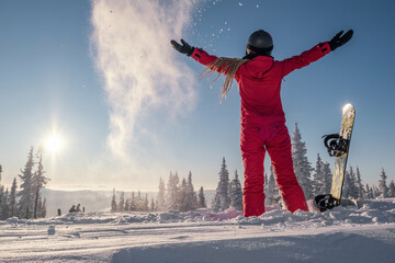 Woman snowboarder standing in  snowy forest, holding her hands up. Moments of freedom and...