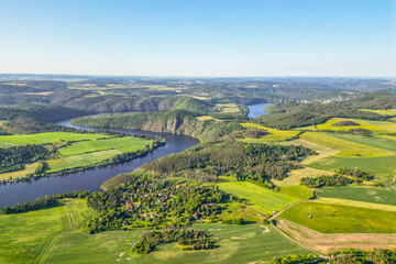 Fototapeta premium Curves of Vltava river in green landscape on sunny summer day. Aerial drone view.