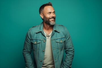 Portrait of a blissful man in his 40s sporting a rugged denim jacket against a pastel teal background. AI Generation