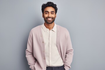 Obraz premium Portrait of a content indian man in his 20s wearing a chic cardigan against a pastel gray background. AI Generation