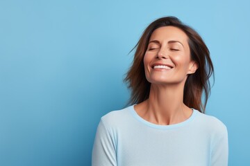 Portrait of a joyful woman in her 40s sporting a long-sleeved thermal undershirt against a soft blue background. AI Generation - obrazy, fototapety, plakaty