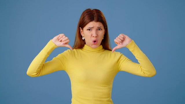Displeased woman shows dislikes with thumb-down and waves hands