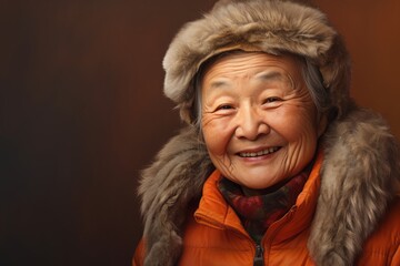 Portrait of a grinning asian elderly woman in her 90s dressed in a warm ski hat against a soft brown background. AI Generation - Powered by Adobe