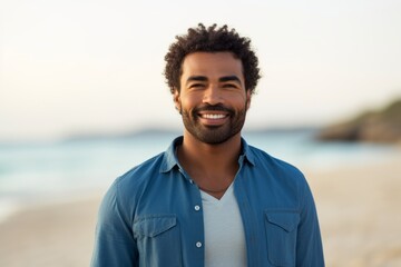 Portrait of a glad afro-american man in his 30s sporting a versatile denim shirt against a sandy beach background. AI Generation - obrazy, fototapety, plakaty