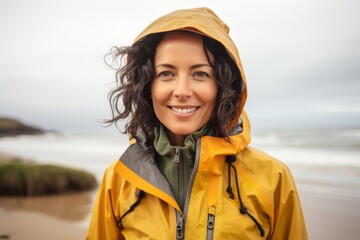 Portrait of a happy woman in her 40s sporting a waterproof rain jacket against a sandy beach background. AI Generation