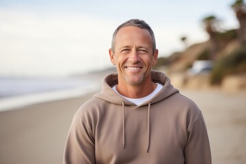 Fototapeta premium Portrait of a grinning man in his 40s dressed in a comfy fleece pullover against a sandy beach background. AI Generation