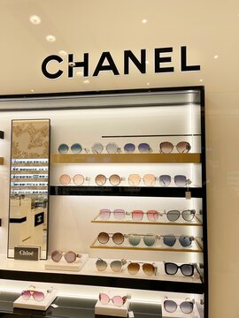 Sunglasses of famous brands on counter of optics store. Famous brands: Chanel, Chloe. Latest collection of frames and sunglasses from fashion luxury French houses. Rack in official retailer store.