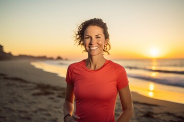Portrait of a smiling woman in her 30s wearing a moisture-wicking running shirt against a stunning sunset beach background. AI Generation