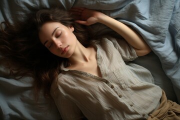 Woman sleeping. High angle view of beautiful young woman lying in bed and keeping eyes closed while covered with blanket.