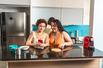Women in the kitchen using a smartphone to check the items in a recipe.