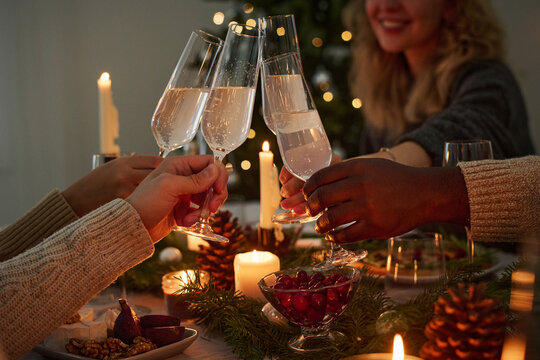 Closeup of hands of unknown group of people raising toast together during christmas celebration