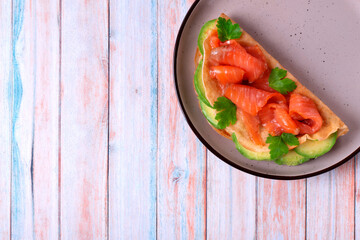 Crepe with salted trout and avocado on ceramic plate. Breakfast meal. Top view. Copy space