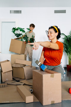Smiling mother and son packaging and carrying boxes in new apartment