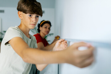 Serious boy helping mom to take measurement