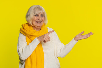 Senior old woman showing thumbs up and pointing right empty place, advertising area for commercial...