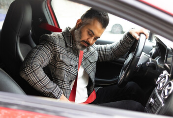 Focused Indian businessman wearing seat belt for safety in car