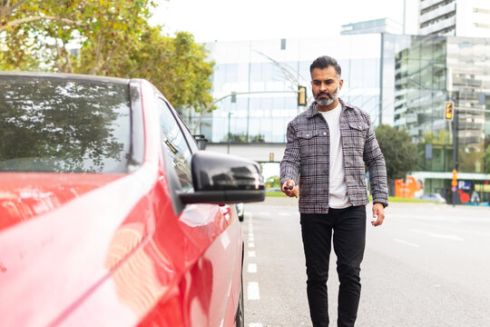 Indian businessman opening car with remote key on street